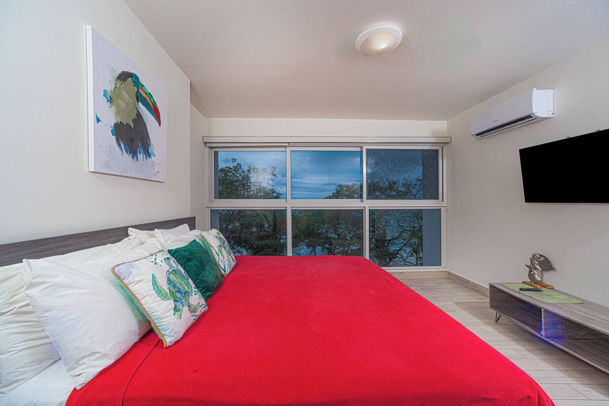 Een slaapkamer met een groot bed, een schilderij aan de muur, een raam met uitzicht en een airconditioning.