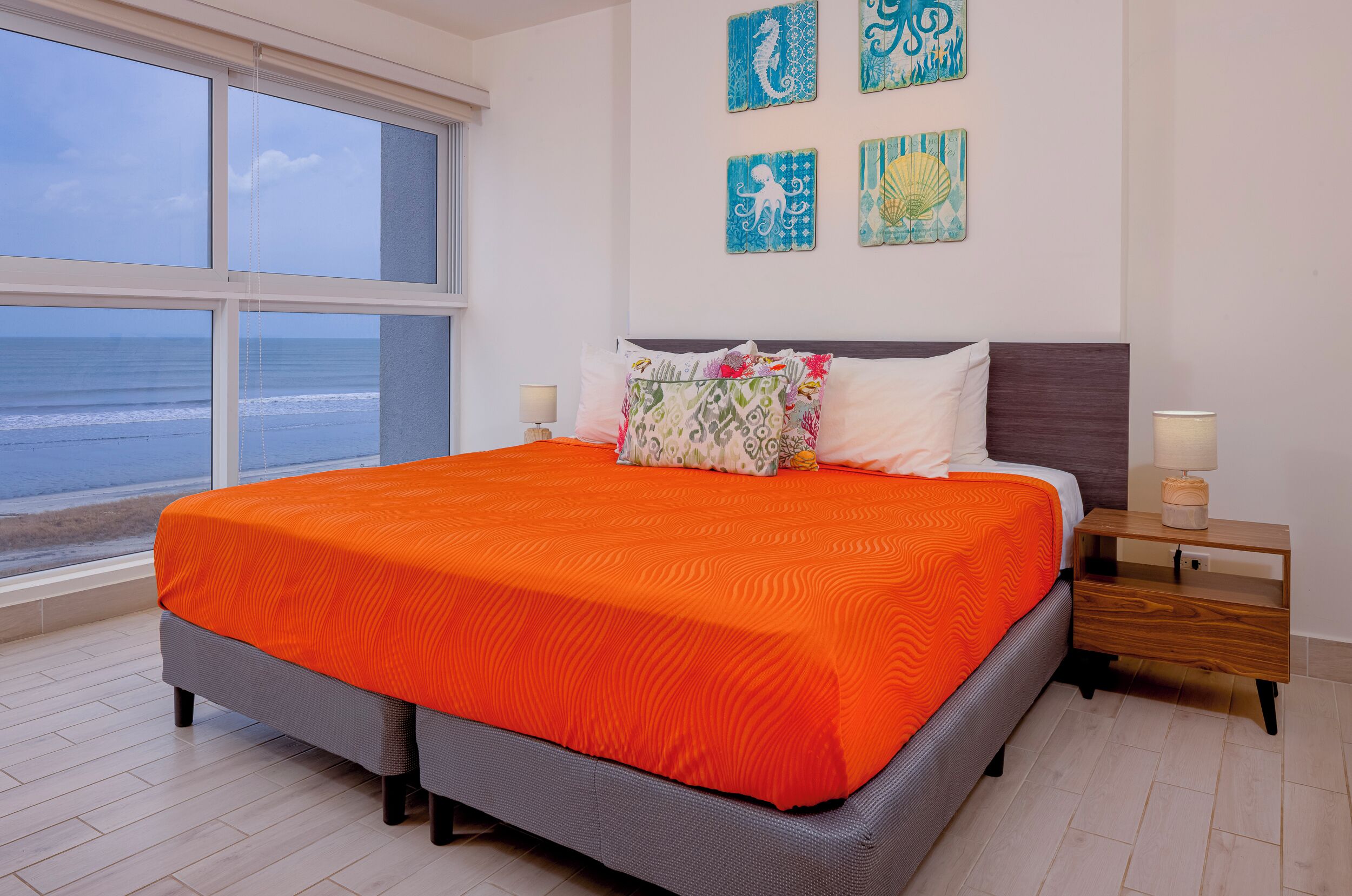 Un dormitorio con una cama grande, vista al océano y decoración en las paredes.