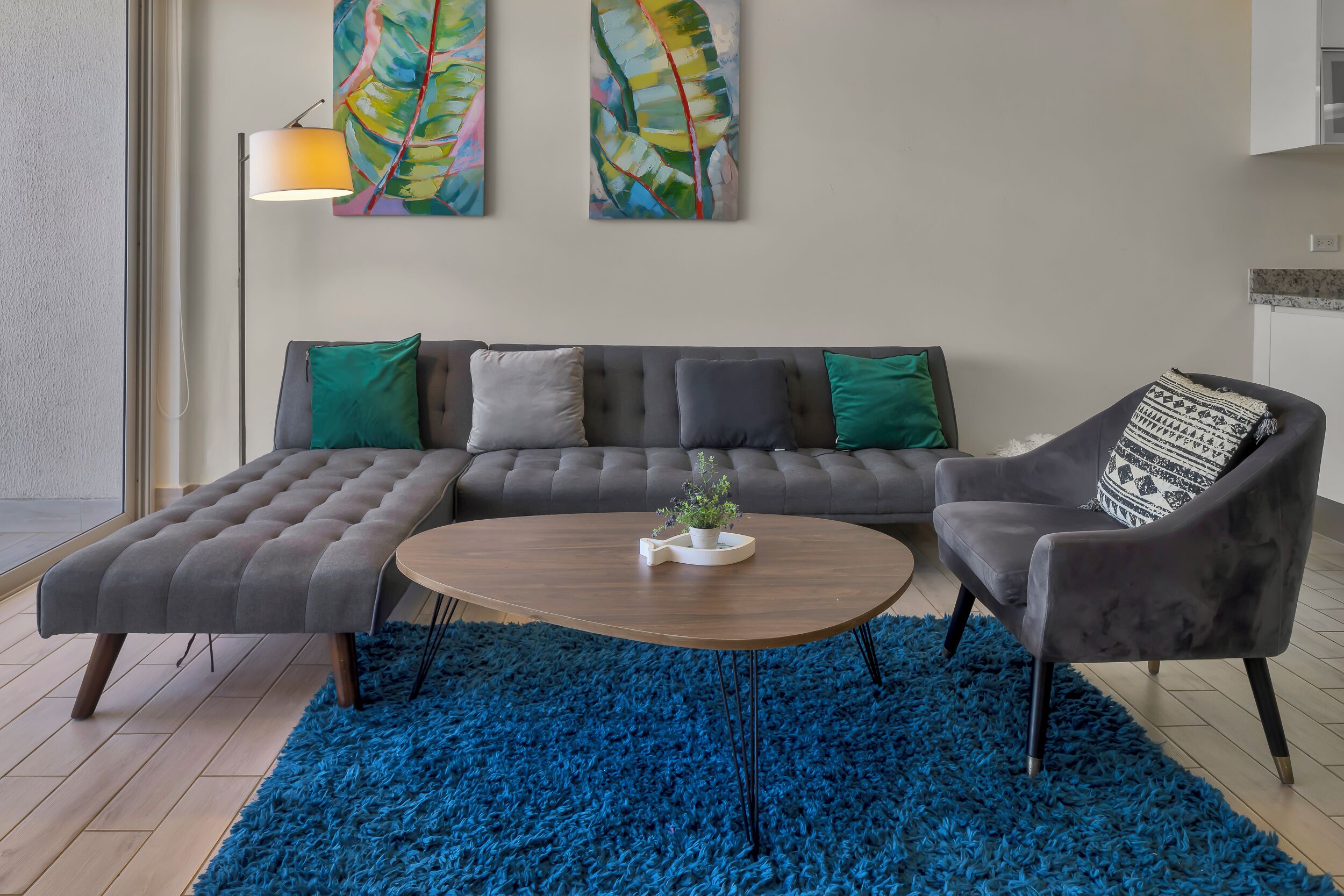 Una sala moderna con un sofá modular, una mesa de centro redonda y una alfombra de pelo alto azul.