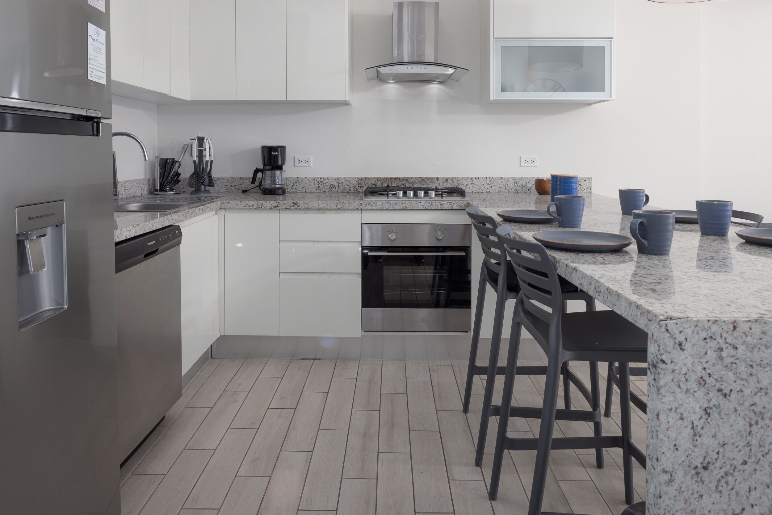 A modern kitchen with stainless steel appliances, white cabinets, and a granite countertop.