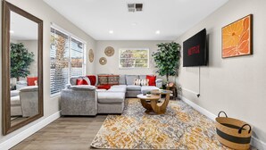 A modern living room with a sectional sofa, a coffee table, and a TV mounted on the wall. - Family Luxury Escape Heated Pool, Spa, Mini Golf, Arcade (Largo)