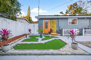 Une petite maison de plain-pied, à l’extérieur gris et à la porte jaune.