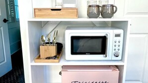Una kitchenette equipada con microondas, cafetera y refrigerador pequeño.