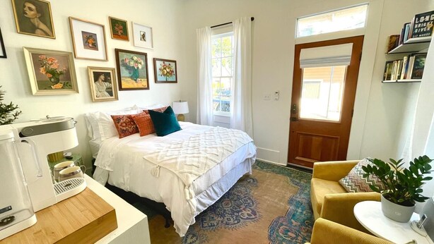 Un dormitorio acogedor con cama, cafetera, alfombra y estantería.