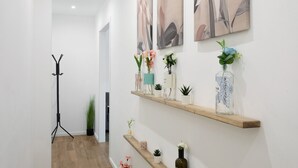 A hallway with a tripod stand, potted plants, and shelves with vases and small plants. - Casa Belfiore Amacardo with Private Terrace (Giarre)