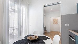 A modern dining area with a round table, chairs, and a view through a window with sheer curtains. - Casa Belfiore Amacardo with Private Terrace (Giarre)
