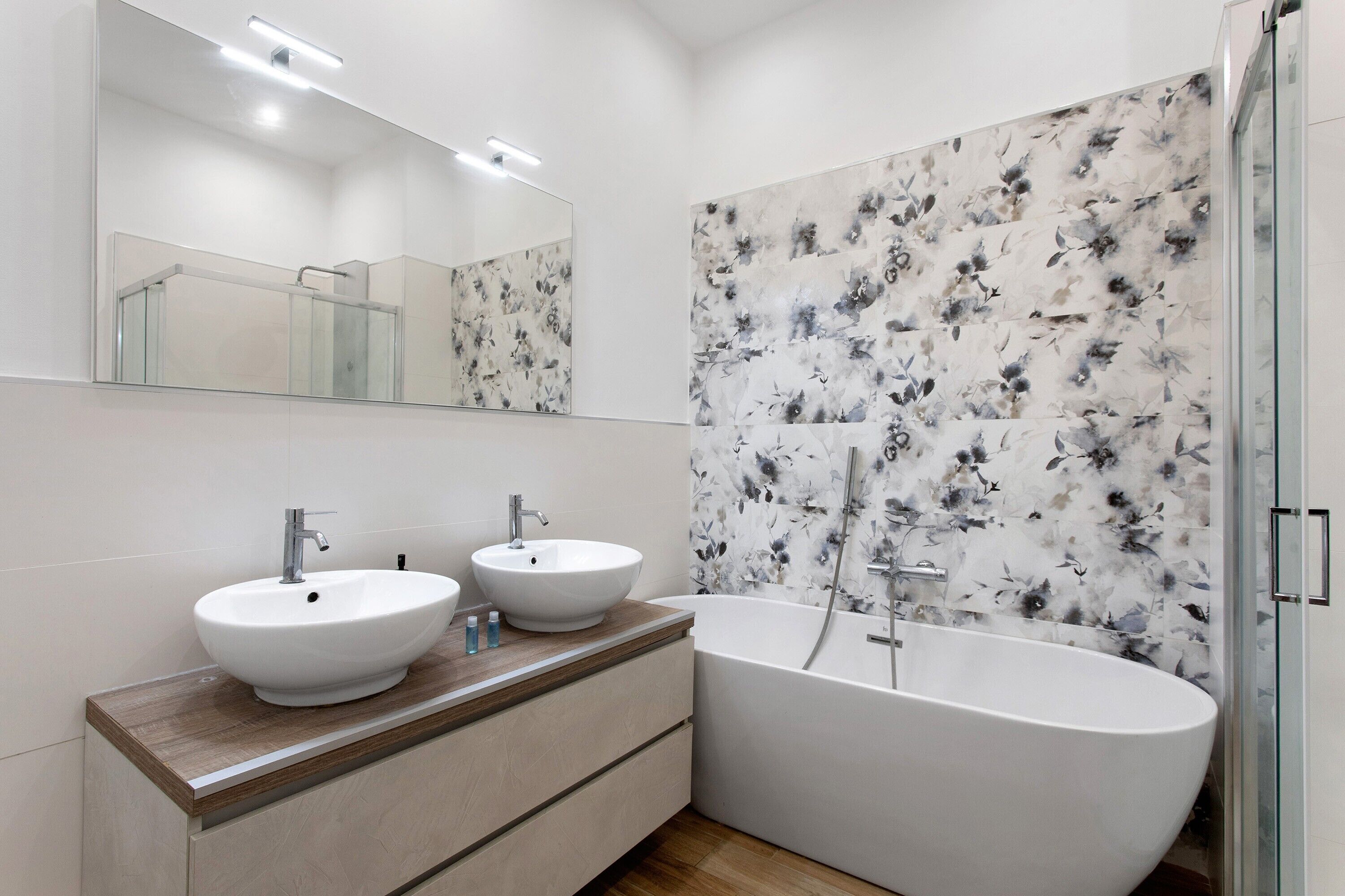 A modern bathroom with two sinks, a bathtub, and a shower.