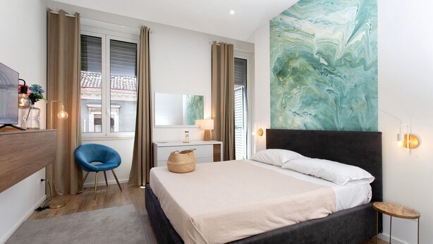 A bedroom with a bed, a desk, a chair, a lamp, and a wall painting. - Casa Belfiore Amacardo with Private Terrace (Giarre)