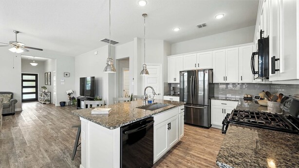 A modern kitchen with white cabinets, a stainless steel refrigerator, granite countertops, and a gas stove. - Shepherd’s Path | Pet-Friendly 3BR/2BA Monthly Rental in New Braunfels (New Braunfels)
