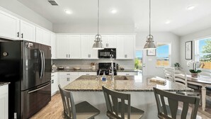 A modern kitchen with white cabinets, a black refrigerator, granite countertops, and pendant lighting. - Shepherd’s Path | Pet-Friendly 3BR/2BA Monthly Rental in New Braunfels (New Braunfels)