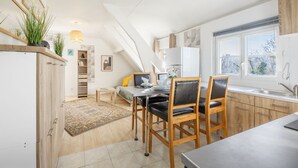 A modern kitchen with a dining area, wooden cabinets, and a large window providing natural light. - Du côté de Giverny - Avec Parking Privé (Bennecourt)