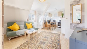 A modern living room with a green sofa, yellow pillows, a coffee table, and a patterned rug. - Du côté de Giverny - Avec Parking Privé (Bennecourt)