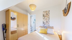 A bedroom with a bed, a wardrobe, a hanging light fixture, and a wall-mounted decorative piece. - Du côté de Giverny - Avec Parking Privé (Bennecourt)