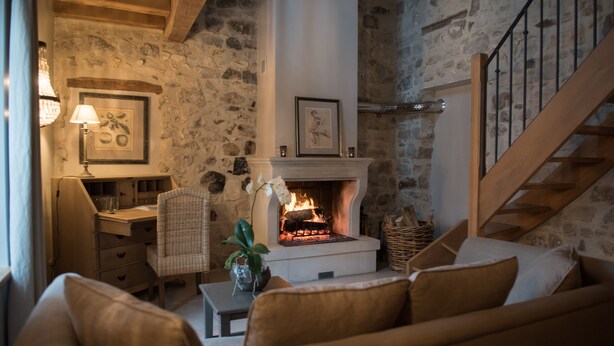A cozy living room with a stone wall, a fireplace, a wooden staircase, and a comfortable seating area. - Le Gite de Caroline - Avec Parking Privé (Fère-en-Tardenois)