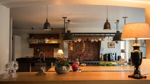 A modern kitchen with pendant lighting, a wooden countertop, and a red kettle. - Le Gite de Caroline - Avec Parking Privé (Fère-en-Tardenois)