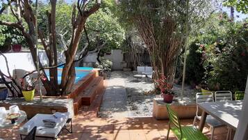 A patio area with a pool, outdoor seating, and potted plants.