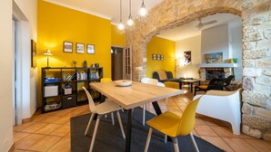 A dining area with a wooden table, yellow chairs, and a stone archway. - Soleil Provençal - Avec piscine privée (Avignon)