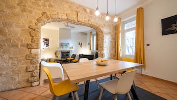 A dining area with a stone archway, a wooden table, and yellow and white chairs.