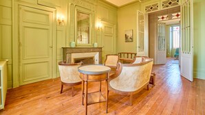 A room with green walls, a fireplace, and a chandelier. There are four wicker chairs and a round table. - Château Tour Chapoux - Piscine privée (Saint-Antoine-du-Queyret)