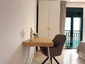 A room with a wooden table, a grey chair, a white wardrobe, and a view through a green door. - La Pituca II Apartment (Playa Blanca)