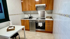 Una cuina compacta amb armaris de fusta, un forn d'acer inoxidable i un rentaplats.