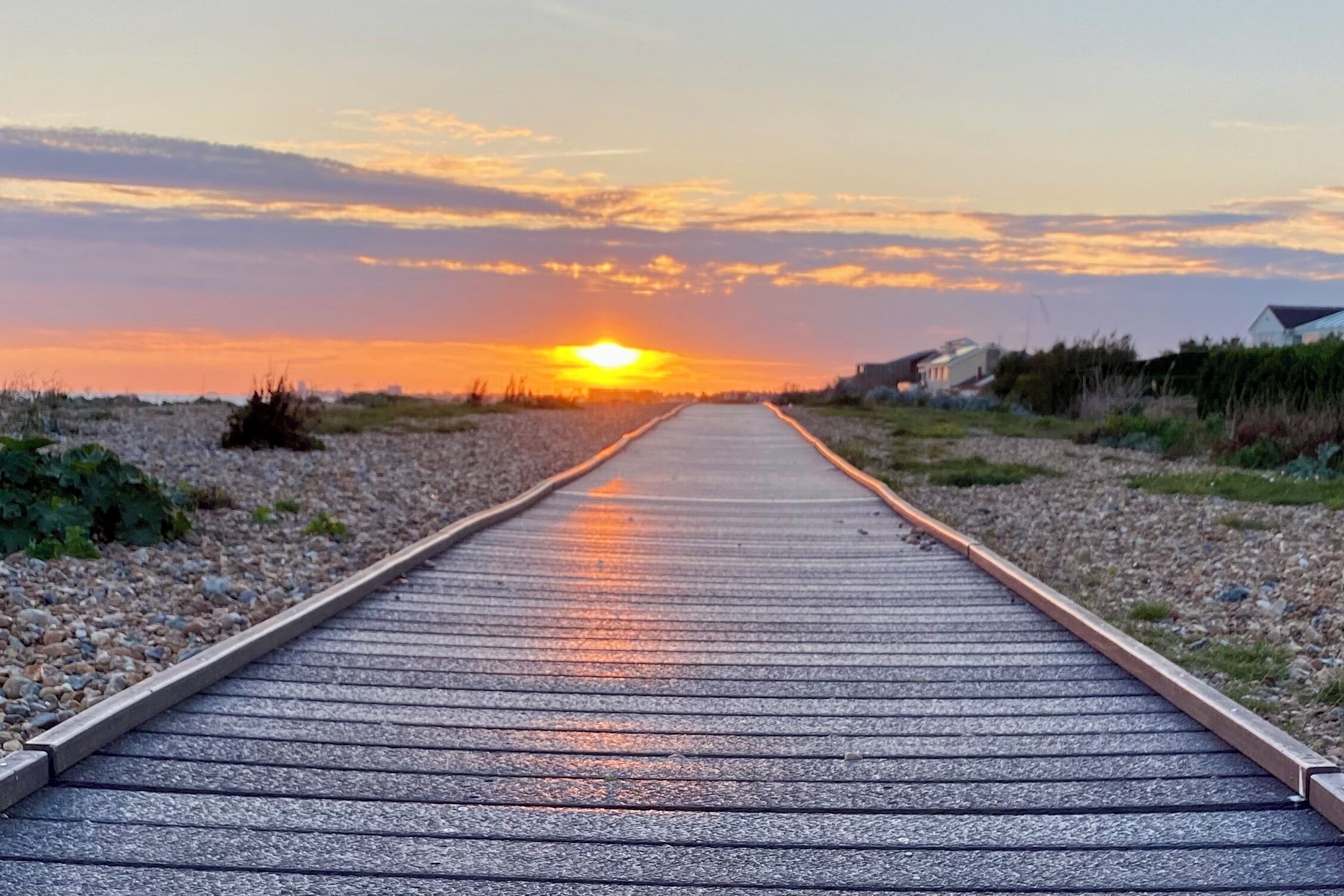 Un camino pavimentado que lleva hacia un atardecer.