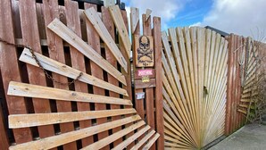 A wooden fence with a skull and crossbones sign, a chain, and a 'POST HERE' sign.