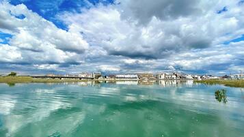 Ruhige Wasserfläche, die Gebäude und einen bewölkten Himmel spiegelt.