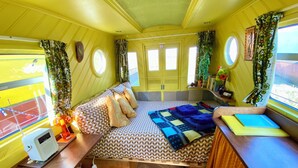 A compact, well-lit room with a bed, bedside table, and a window.