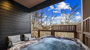 Ein Whirlpool mit einer Holzterrasse und Blick auf Bäume und Himmel.