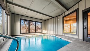 Ein überdachter Pool mit großen Fenstern und Blick auf Bäume.