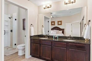 Een badkamer met een wastafelmeubel met dubbele wastafel, een douche en een toilet.
