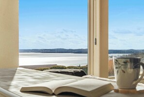 A room with a view of a lake, a book, and a mug on a windowsill. - Majestic Retreat Stay for 6 (Branson)