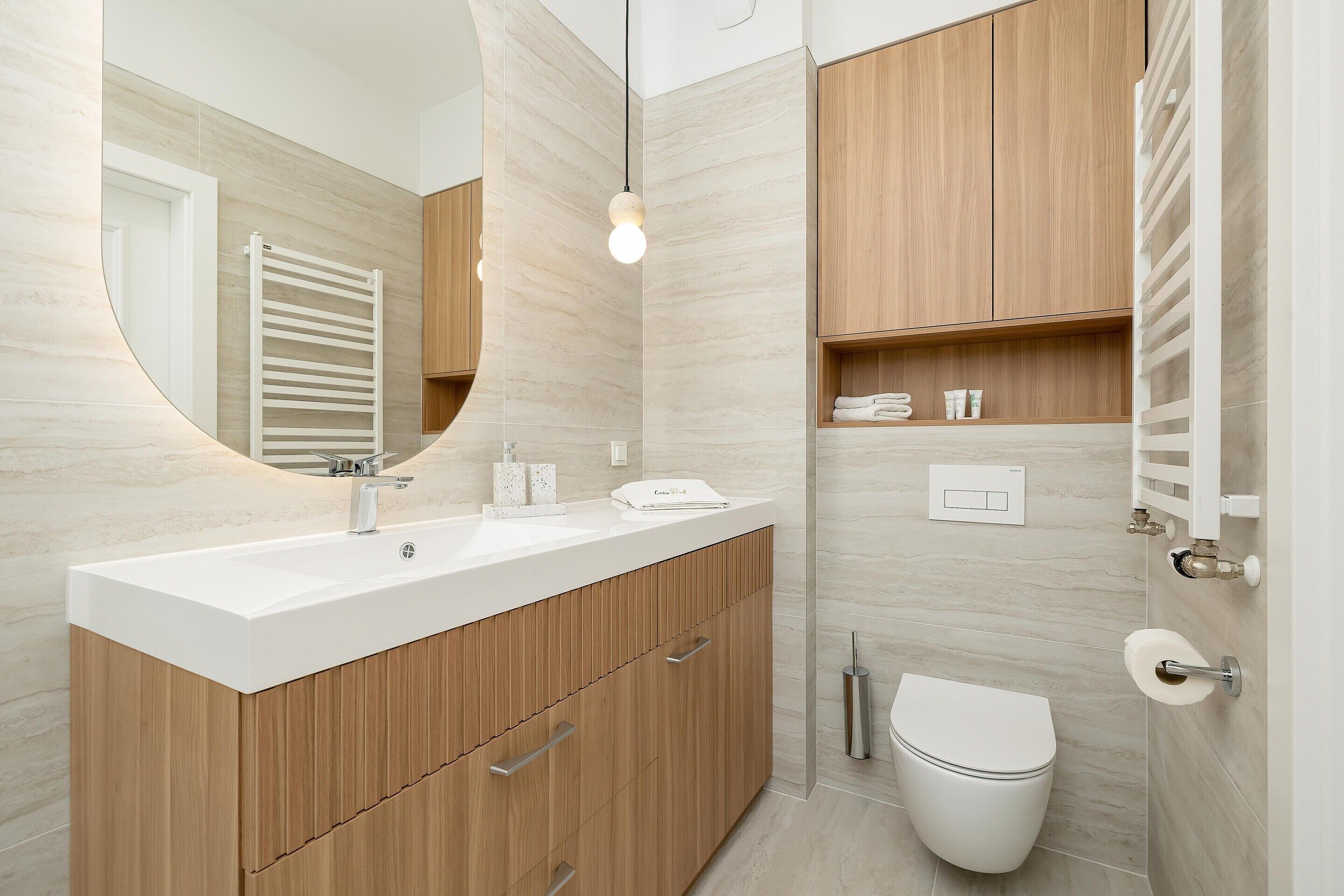 Une salle de bain moderne avec un meuble-lavabo en bois, un lavabo blanc, un miroir et des toilettes.