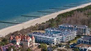 Un hotel costero con varias edificaciones, una playa y un muelle.