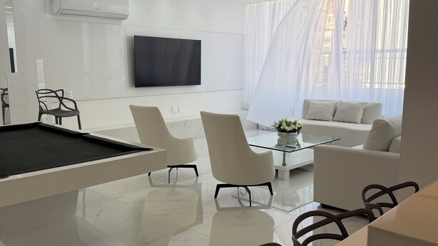 Ein modernes Wohnzimmer mit Flachbildfernseher, Billardtisch und Sofa.