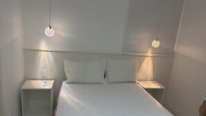 Ein schlichter Schlafzimmerbereich mit einem großen Bett, zwei Nachttischen und zwei Wandlampen.