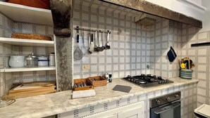 A kitchen with a tiled backsplash, a gas stove, and various kitchen utensils. - Zanobi 75 - Three Bedroom Apartment, Sleeps 7 (Firenze)