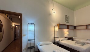 A hotel room with two single beds, a standing lamp, a bedside table, a shelf unit, and a small desk. - Zanobi 75 - Three Bedroom Apartment, Sleeps 7 (Firenze)