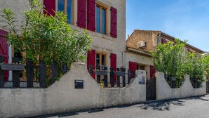 Un immeuble avec des volets rouges, une façade en béton et une rue devant.