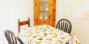 A dining table with a bird-patterned tablecloth, two wooden chairs, a wooden cabinet with glass doors, and a map on the wall. - Quiet 2-Bedroom Upper Floor in Bala Cynwyd | Private Entrance & Parking (Bala Cynwyd)