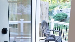 Eine Glastür führt zu einem Balkon mit einem Stuhl und einem weißen Zaun.
