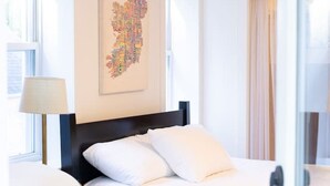 Ein Schlafzimmer mit einem Bett, einem Sessel, einer Lampe und einer Karte an der Wand.