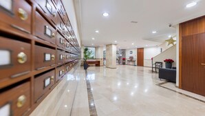 A hotel lobby with a long row of wooden filing cabinets, a reception desk, and a staircase with a star decoration. - Beachfront Marbella Apartment With Balcony (Marbella)