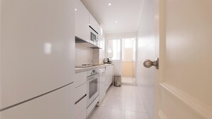 A modern kitchen with white cabinetry, a stainless steel oven, and a microwave. - Beachfront Marbella Apartment With Balcony (Marbella)