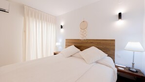 A neatly made bed with pillows, a bedside lamp, and a wall-mounted dreamcatcher. - Beachfront Marbella Apartment With Balcony (Marbella)
