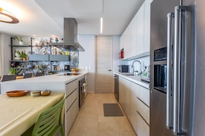 A modern kitchen with a central island, stainless steel appliances, and a variety of decorative items on shelves. - Calablanca T2-506 in Cartagena de Indias (Cartagena)