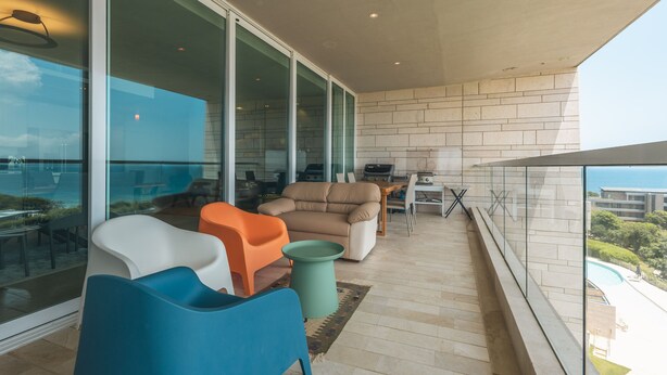 Ein Balkon mit einer Couch, Stühlen und einem kleinen Tisch.