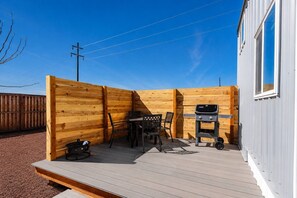 A wooden deck with a barbecue grill and outdoor furniture. - Zion Red-Rock Romance - Tiny Home with Private Deck (Apple Valley)