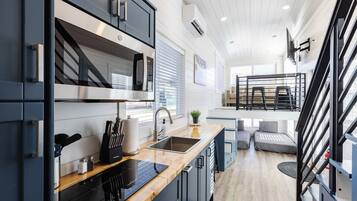 A modern kitchen with a built-in microwave, a sink, and a stove. There is a dining area with a table and chairs.